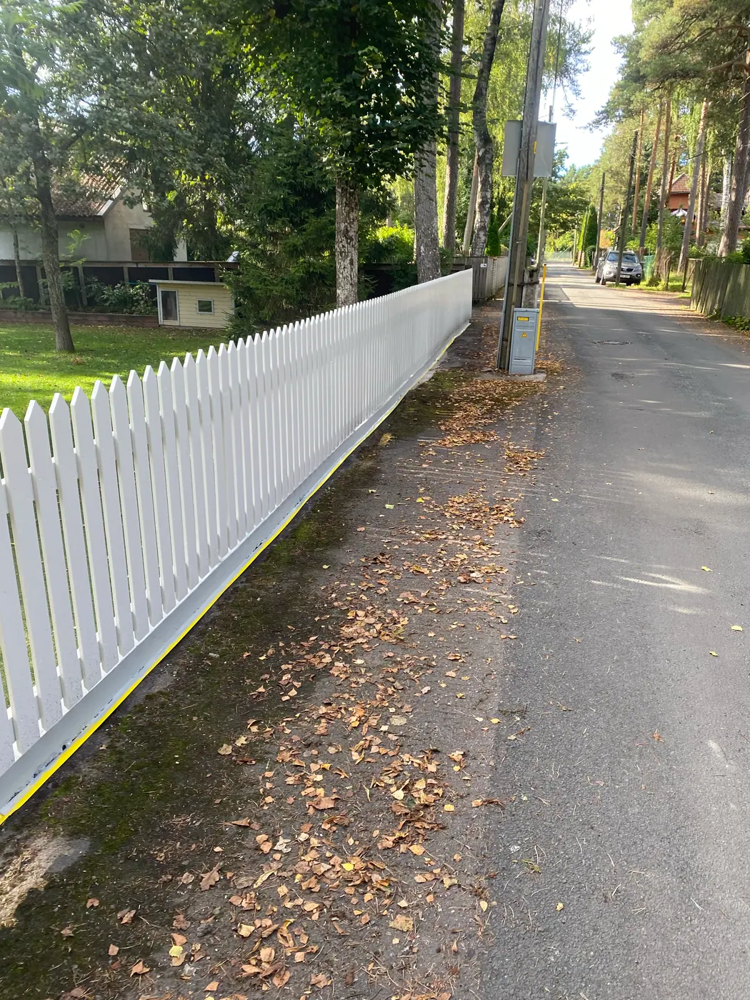 Ülevaade renoveeritud ja värvitud puidust piirdeaiale tänava poolt